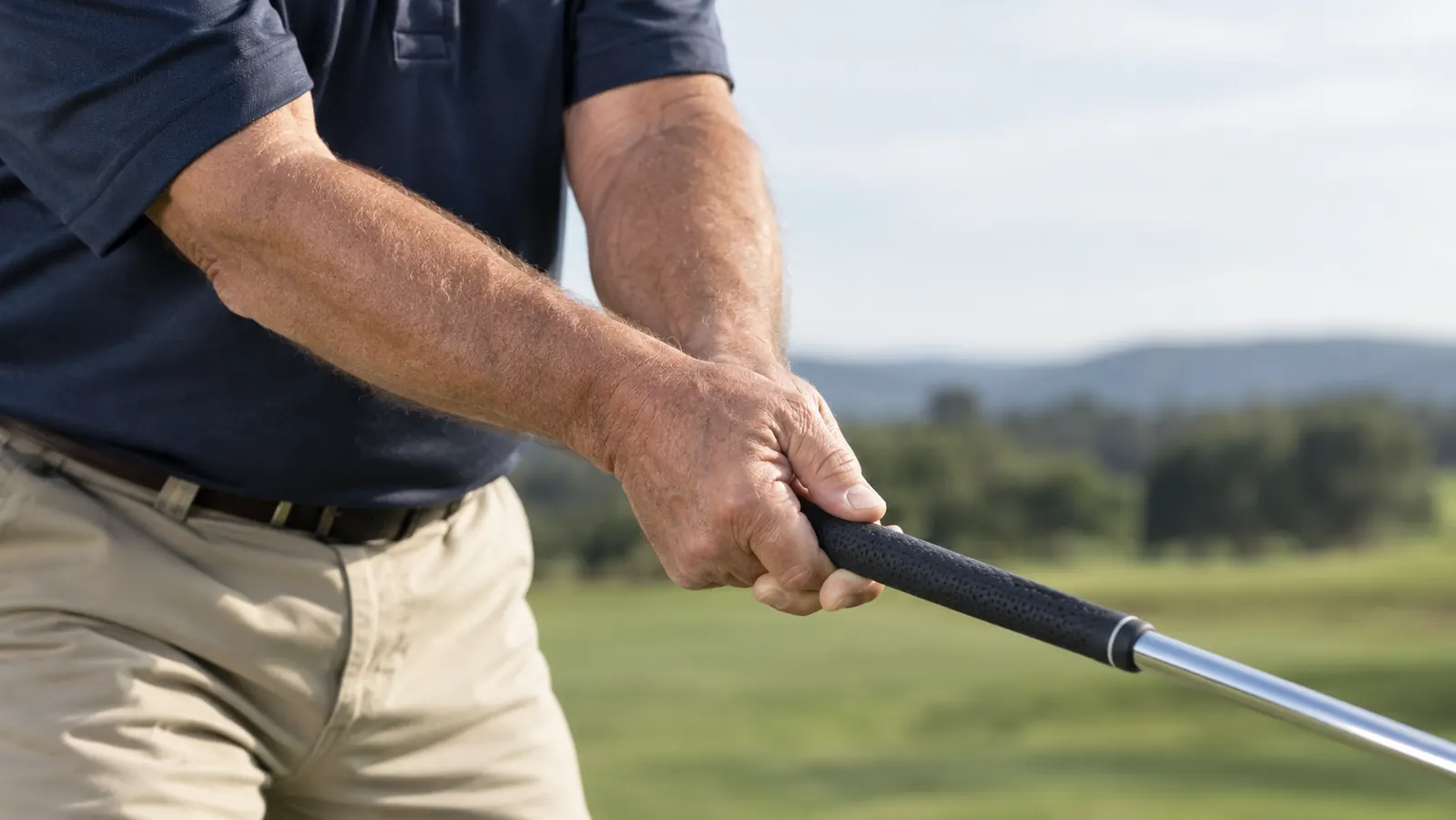 Close view of a golfer's hands holding a weighted swing trainer during a practice swing